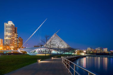 Milwaukee silueti alacakaranlıkta Michigan Gölü ve rıhtımında şehir yansıması ile.