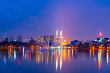 Kuala Lumpur şehrinin gece manzarası, sudaki yansıma ile gökyüzü.