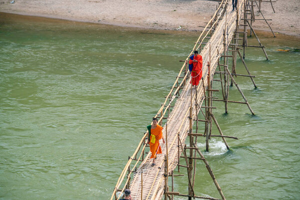ЛУАНГ-ПРАБАНГ, ЛАОС - 10 ФЕБ: Буддийские монахи пересекают бамбуковый мост через реку, Луанг-Прабанг, Лаос. on Февраль 10, 2017
