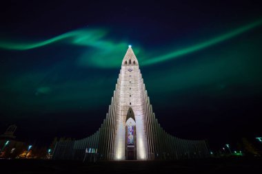 Kuzey ışıkları Reykjavik İzlanda 'daki kilisenin üzerinde parlıyor.