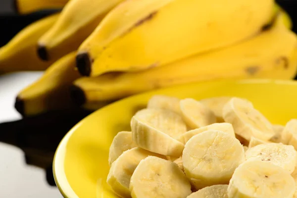 plate with banana slices and whole bananas in the background