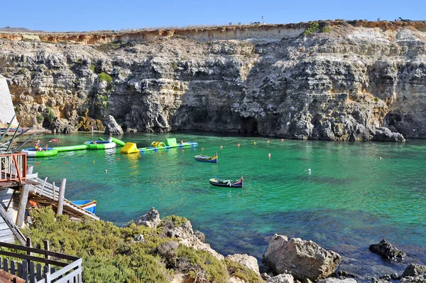 Bay of the island of Gozo with rocks and turquoise sea and playing with people