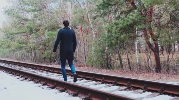 在森林里一个英俊的年轻人走过铁轨的镜头 — 图库视频影像