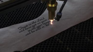 Lazer makinesinin yakın çekim görüntüleri. Deri kağıda kutsal İncil 'den bir alıntı.