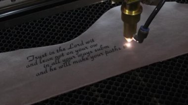 Lazer makinesinin yakın çekim görüntüleri. Deri kağıda kutsal İncil 'den bir alıntı.