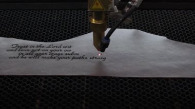 Lazer makinesinin yakın çekim görüntüleri. Deri kağıda kutsal İncil 'den bir alıntı.