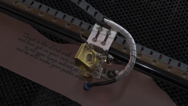 レーザー機械のクローズアップ映像が革シートに聖書の引用を彫る — ストック動画