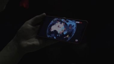 Dünya modeliyle akıllı telefon taşıyan adamın yakın çekim görüntüleri.