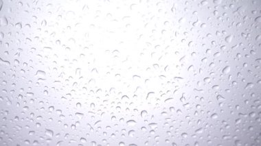 Arka planda bulutlu gökyüzü olan cam üzerindeki yağmur damlalarının yakın plan görüntüleri