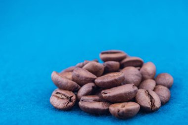 Mavi kabarık halıda kavrulmuş kahve çekirdekleri.