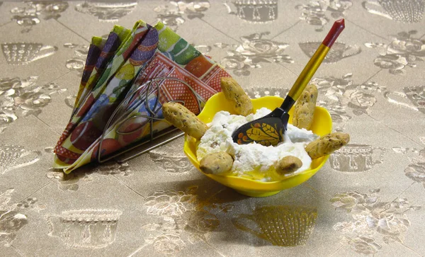 Paskalya tatili. Güzel bir kasede kuru üzümlü süzme peynir. Kurabiye çubukları güneş ışınları şeklinde dizilir. Renkli yumurta resmiyle bezlerin yanında..