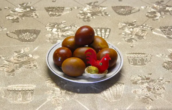 Paskalya tatili. Bir fincan tabağında güzel bir renge boyanmış yumurta. Altın yumurtayla yuvada bir tavuk.