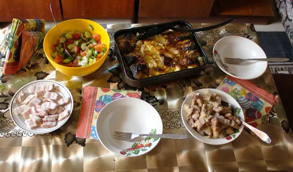 Yemek masası. Fırında tepside pişirilmiş balıklı patates. Soğanlı fırında et parçaları..