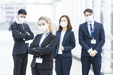 Enfeksiyonu önlemek için maske takan çok uluslu iş adamlarından oluşan bir ekip