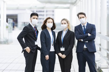 Enfeksiyonu önlemek için maske takan çok uluslu iş adamlarından oluşan bir ekip