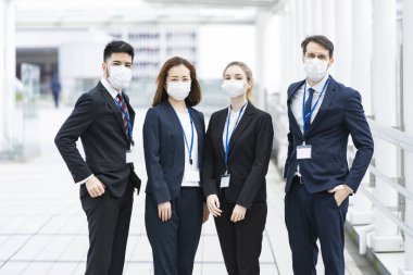 Enfeksiyonu önlemek için maske takan çok uluslu iş adamlarından oluşan bir ekip