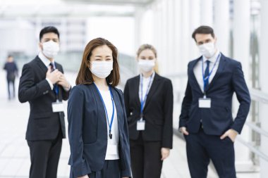 Enfeksiyonu önlemek için maske takan çok uluslu iş adamlarından oluşan bir ekip