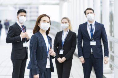 Enfeksiyonu önlemek için maske takan çok uluslu iş adamlarından oluşan bir ekip