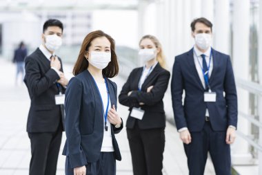 Enfeksiyonu önlemek için maske takan çok uluslu iş adamlarından oluşan bir ekip