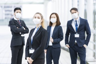 Enfeksiyonu önlemek için maske takan çok uluslu iş adamlarından oluşan bir ekip