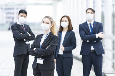 Enfeksiyonu önlemek için maske takan çok uluslu iş adamlarından oluşan bir ekip