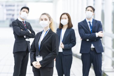 Enfeksiyonu önlemek için maske takan çok uluslu iş adamlarından oluşan bir ekip