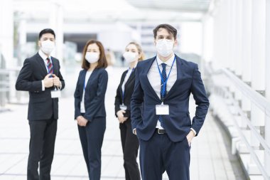 Enfeksiyonu önlemek için maske takan çok uluslu iş adamlarından oluşan bir ekip