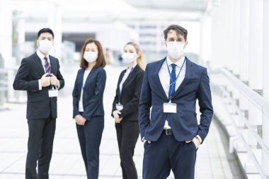 Enfeksiyonu önlemek için maske takan çok uluslu iş adamlarından oluşan bir ekip