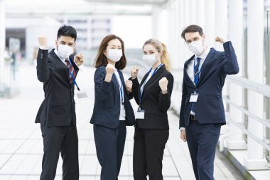 Enfeksiyonu önlemek için maske takan çok uluslu iş adamlarından oluşan bir ekip