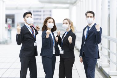 Enfeksiyonu önlemek için maske takan çok uluslu iş adamlarından oluşan bir ekip
