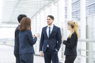 Bir grup iş adamı dışarıda rahatça konuşuyor.