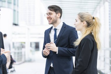 Bir grup iş adamı dışarıda rahatça konuşuyor.