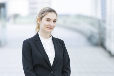 20 'li yaşlarda siyah takım elbiseli bir iş kadınının açık hava portresi.