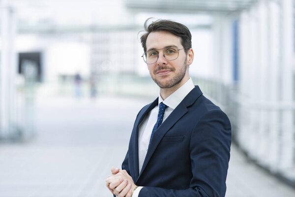 Portrait of a businessman in his thirties wearing a navy suit and glasses