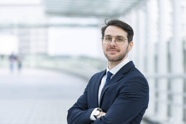Portrait of a businessman in his thirties wearing a navy suit and glasses