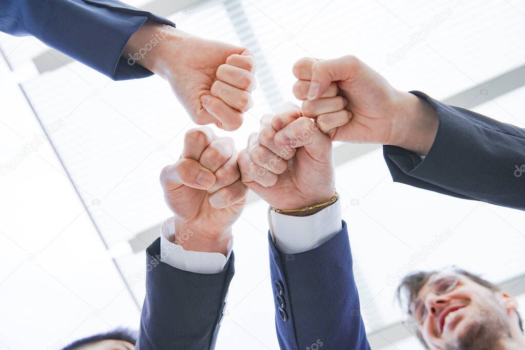 A team of businesspeople overlapping members' hands to strengthen unity