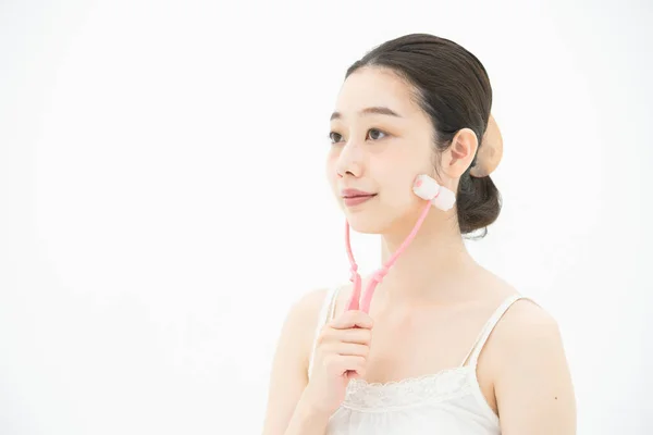 頬に小さなフェイスマッサージ装置を使う若いアジア人女性 — ストック写真