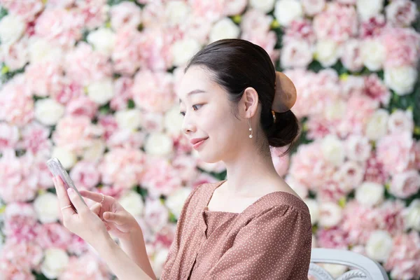 若いアジア人 日本人 の女性の肖像画が花でいっぱいの画面の前に立って — ストック写真