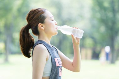Parkta yoga yaparken susuz kalan Asyalı genç bir kadın.