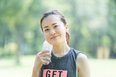 Parkta yoga yaparken susuz kalan Asyalı genç bir kadın.