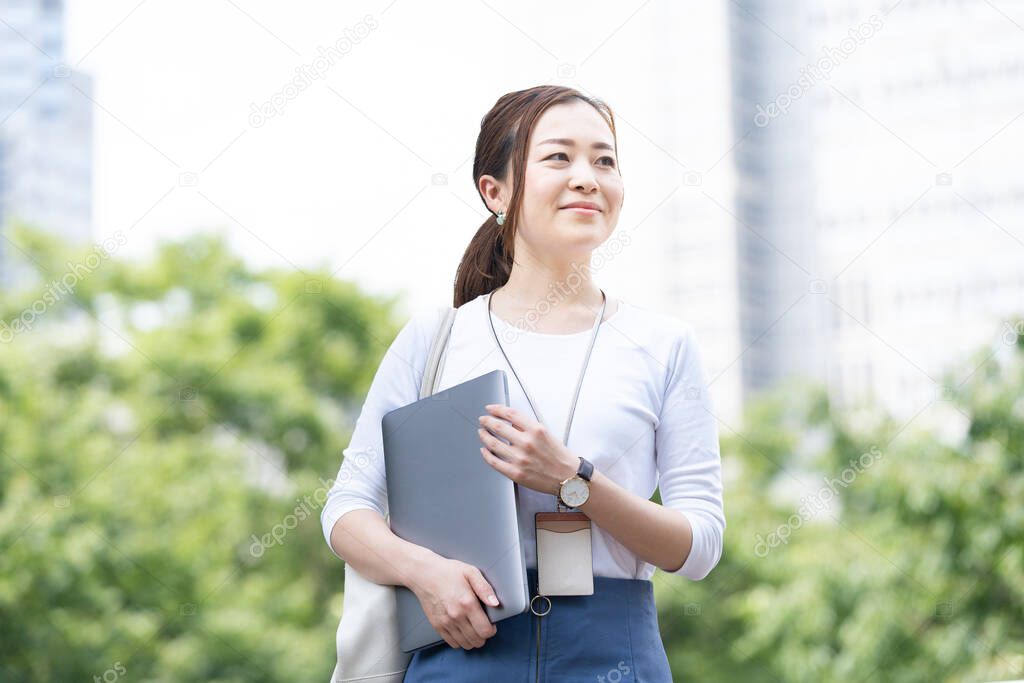 Asian (Japanese) female office worker working outdoors with a laptop