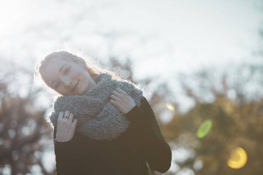 Güneş ışığı parkında nazik bir ifadeyle genç beyaz bir kadın.