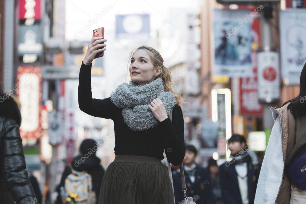 Young European woman sightseeing downtown Shibuya (Tokyo, Japan) with a smile