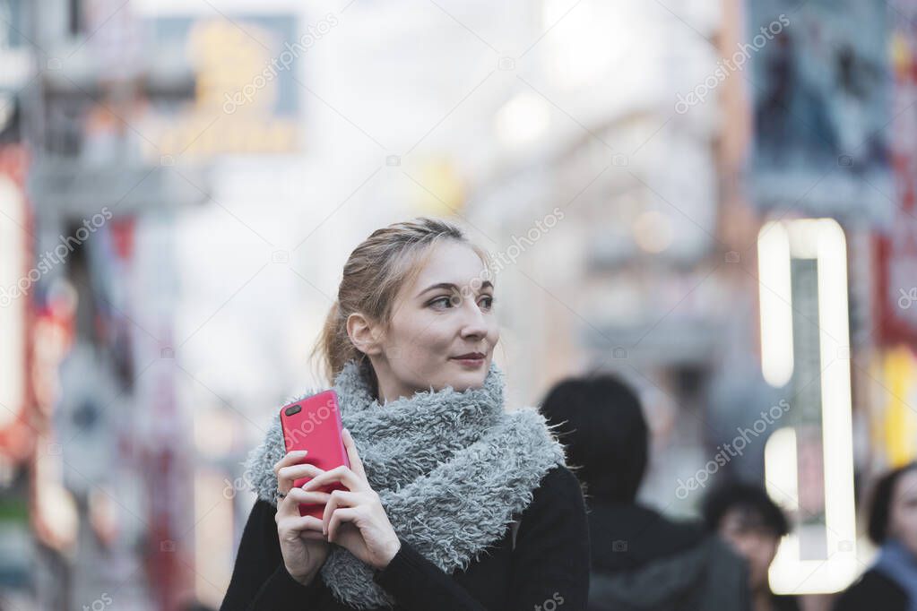 Young European woman sightseeing downtown Shibuya (Tokyo, Japan) with a smile