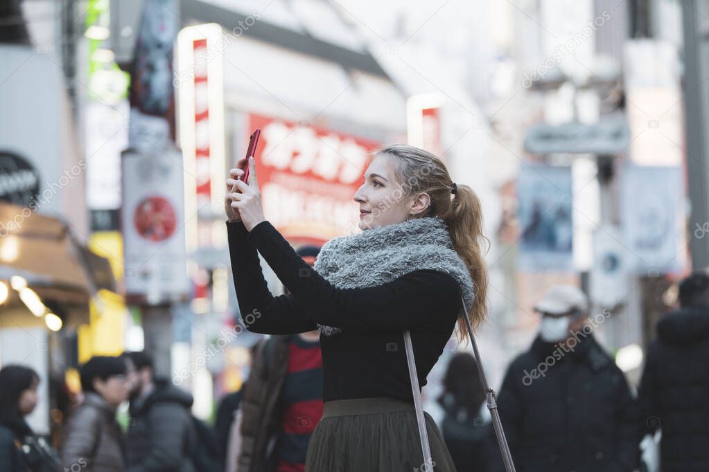 Young European woman sightseeing downtown Shibuya (Tokyo, Japan) with a smile