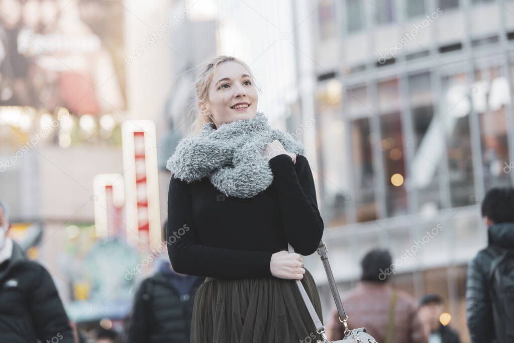 Young European woman sightseeing downtown Shibuya (Tokyo, Japan) with a smile