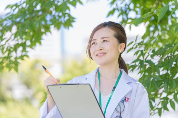 Tıbbi Kayıtları Gülümseyerek Dolduran Asyalı Bir Kadın Doktor — Stok fotoğraf