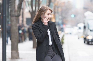 Kafkasyalı genç bir kadın kulağında akıllı telefon olan biriyle konuşuyor.