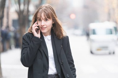 Kafkasyalı genç bir kadın kulağında akıllı telefon olan biriyle konuşuyor.