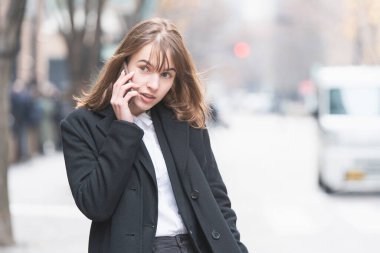 Kafkasyalı genç bir kadın kulağında akıllı telefon olan biriyle konuşuyor.